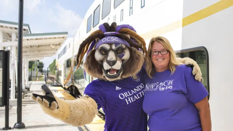 Orlando City's Kingston poses with a SunRail rider at a SunRail station.
