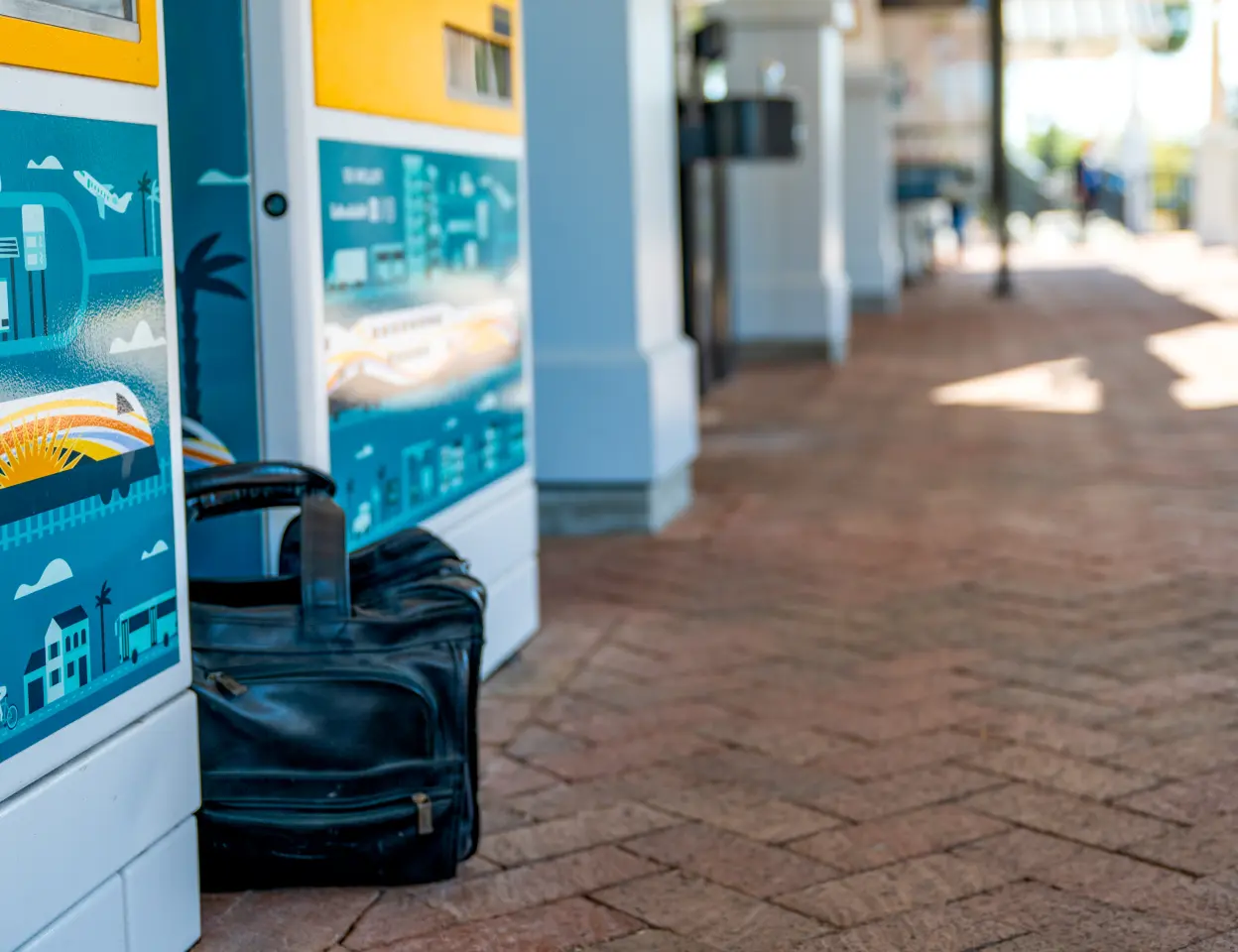 An unaccompanied leather bag sits between two ticket vending machines on SunRail Station platform.