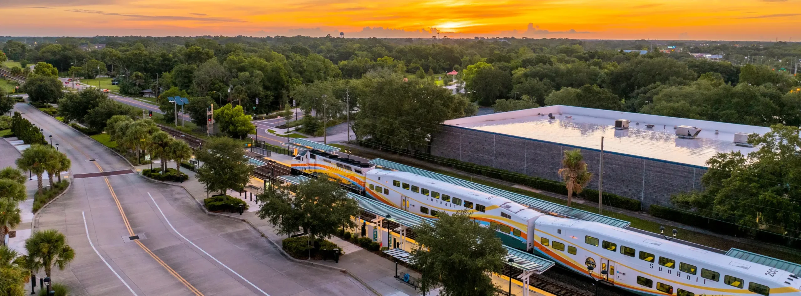 Aerial photo of a SunRail train at the Altamonte Springs SunRail station with the sunrise in the background.