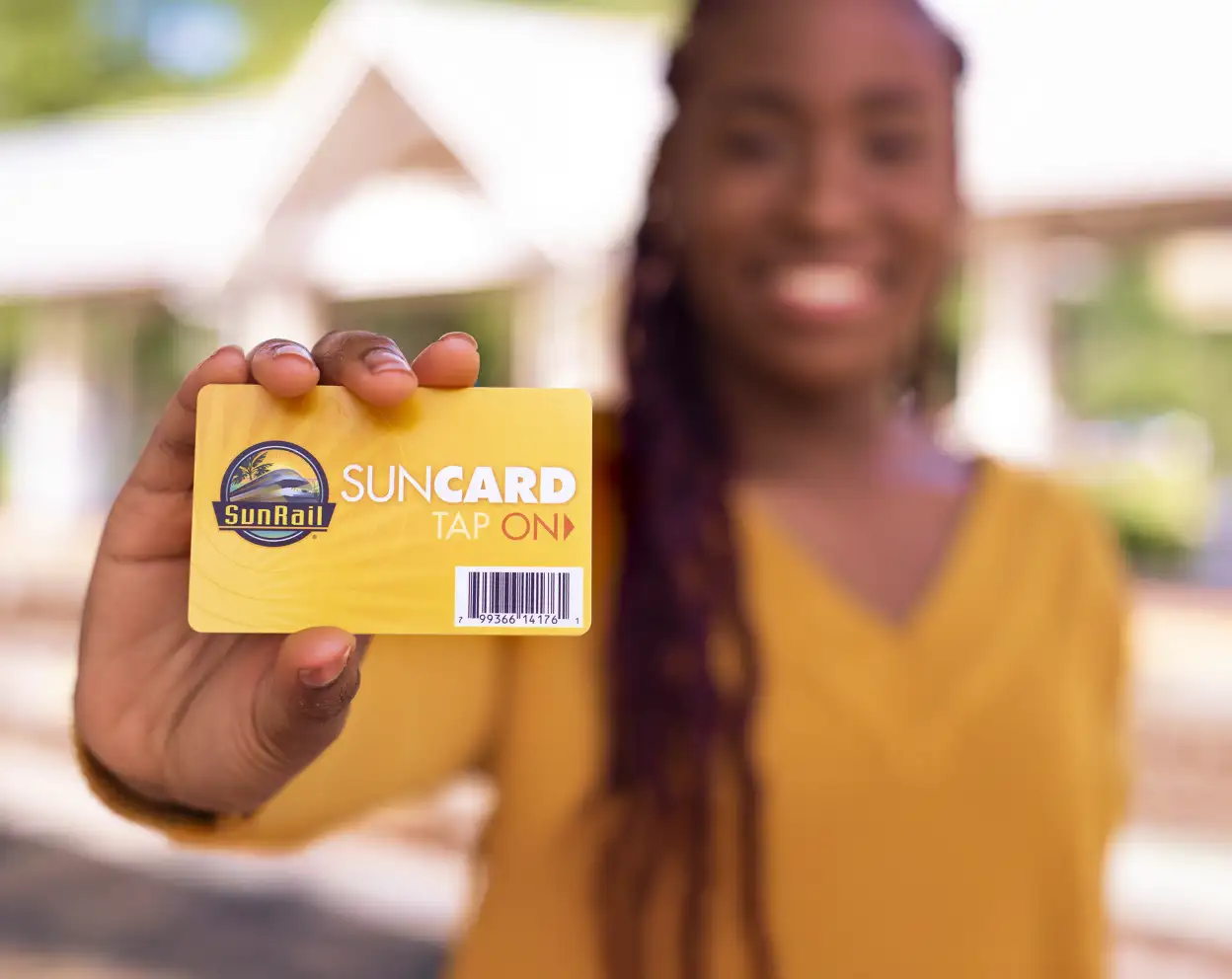 Woman holding yellow legacy SunCard towards camera.