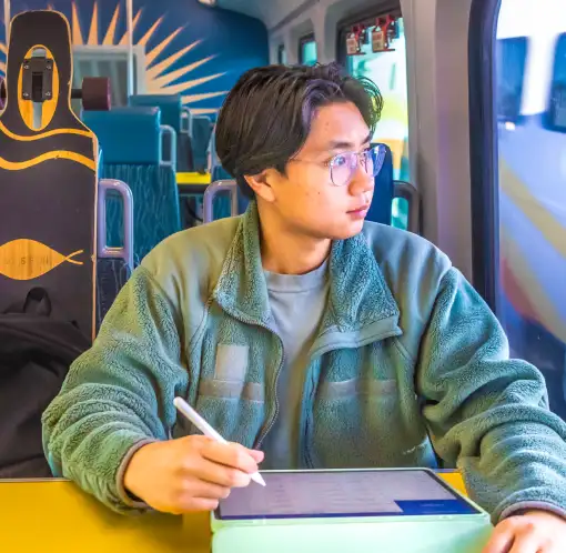 Passenger using a tablet and stylus while riding SunRail and looking out the window.
